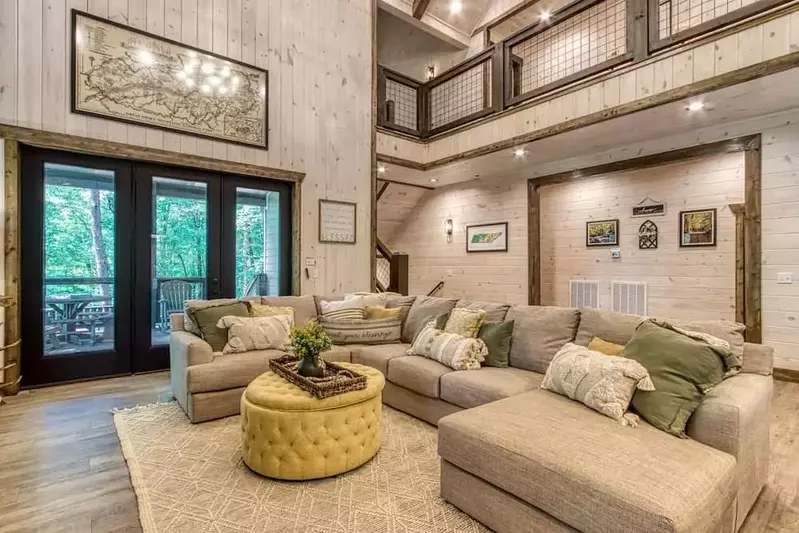 sectional couch and poof with three french doors leading out to a deck in splash to remember pigeon forge cabin